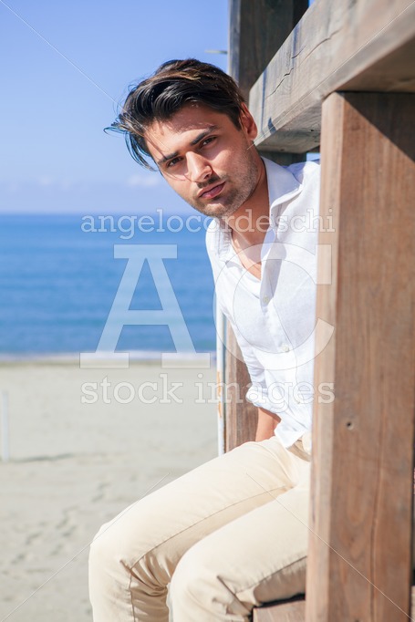 Handsome Man Relaxed At The Sea, Overlooking Sitting On A Wooden Angelo Cordeschi