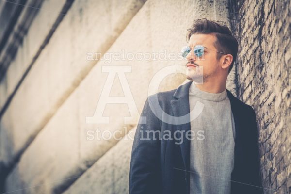 Handsome Stylish Man Leaning On A Wall With Sunglasses And Moder Angelo Cordeschi