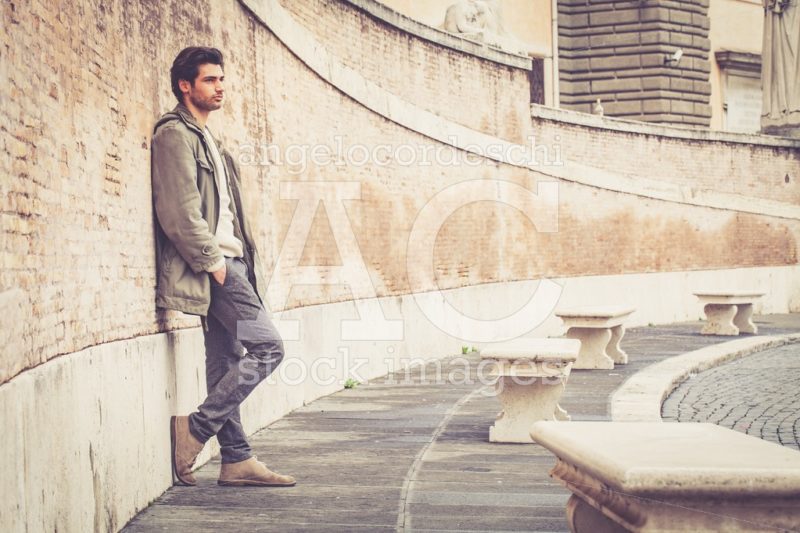 Handsome Young Man Leaning On A Long Wall Outdoors. Casual Cloth Angelo Cordeschi