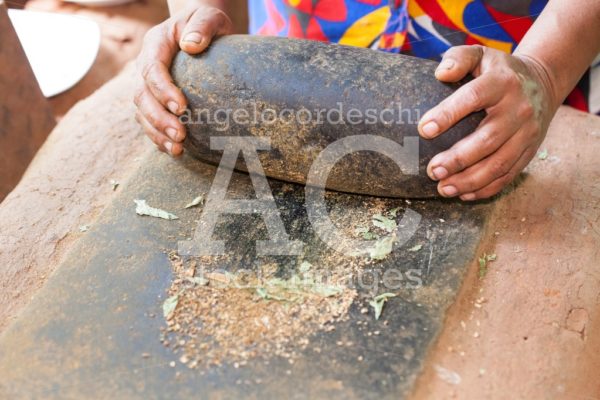 Indigenous woman preparing spices by crushing them with a large - Angelo Cordeschi